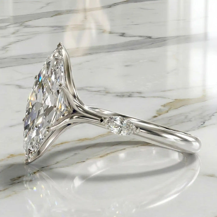 Marquise lab-grown diamond three-stone engagement ring with hidden halo shown on marble display.