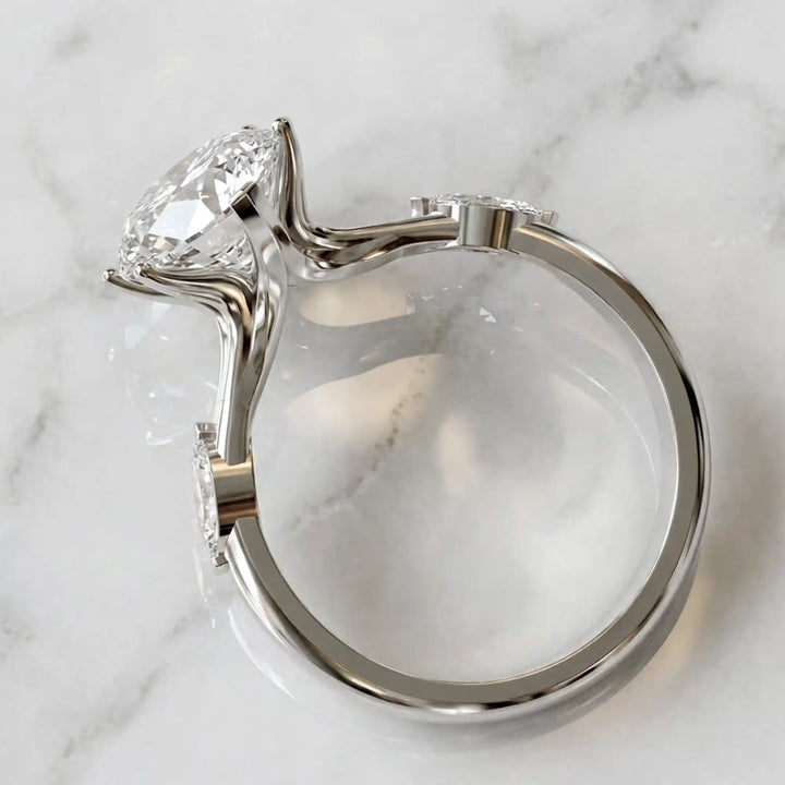 Marquise lab-grown diamond three-stone engagement ring with hidden halo shown on marble display.