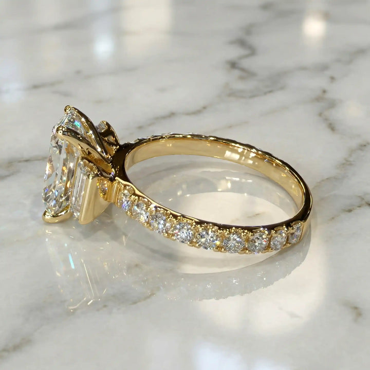 Elongated cushion three stone lab-grown diamond engagement ring displayed on marble surface.