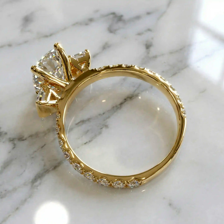 Elongated cushion three stone lab-grown diamond engagement ring displayed on marble surface.