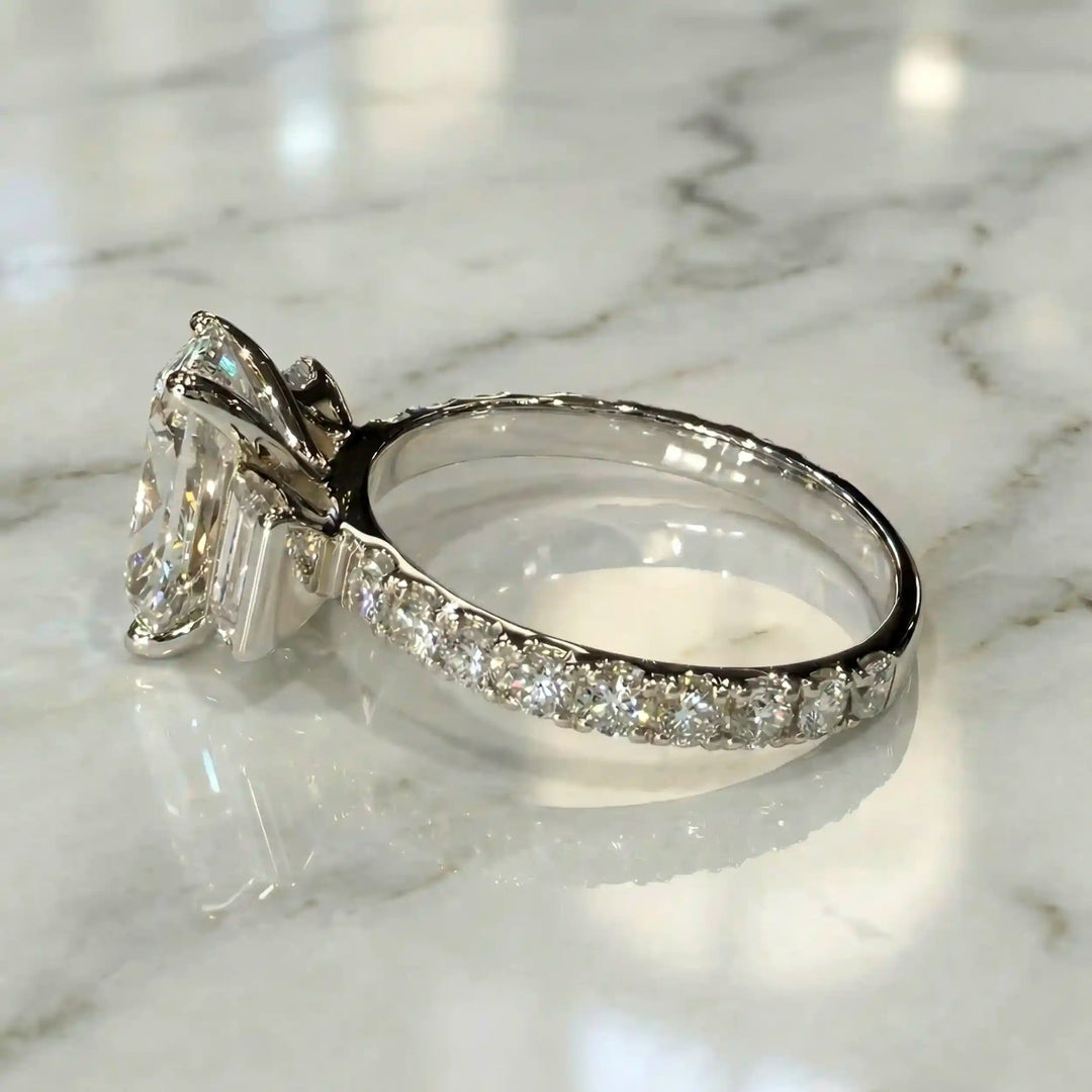 Elongated cushion three stone lab-grown diamond engagement ring displayed on marble surface.