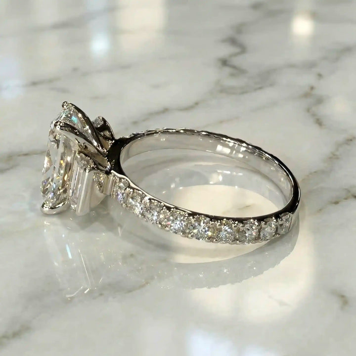 Elongated cushion three stone lab-grown diamond engagement ring displayed on marble surface.