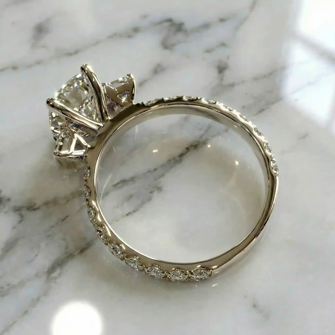 Elongated cushion three stone lab-grown diamond engagement ring displayed on marble surface.