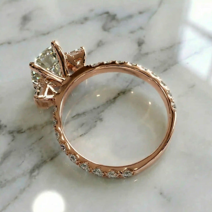 Elongated cushion three stone lab-grown diamond engagement ring displayed on marble surface.