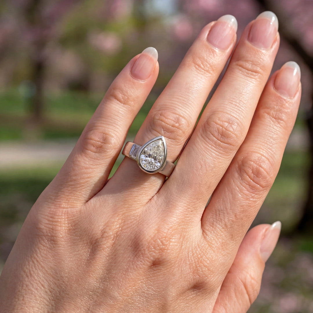 3 carat pear-shaped lab-grown diamond bezel solitaire engagement ring displayed on hand.
