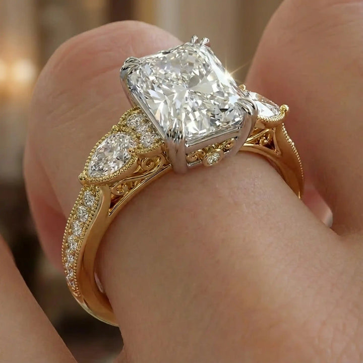 Radiant lab-grown diamond engagement ring with pear side stones displayed on hand.
