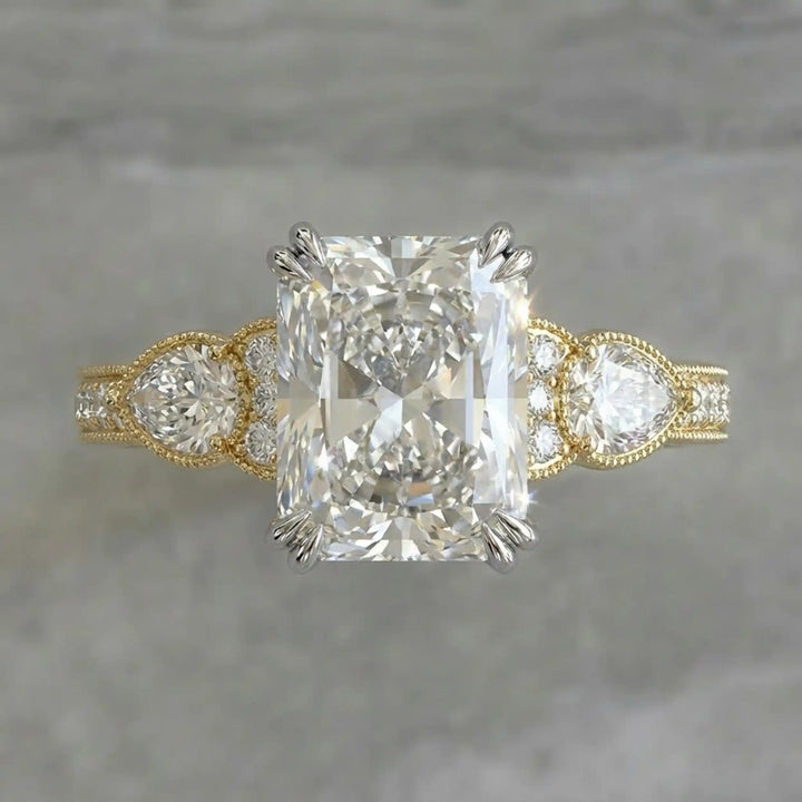 Radiant lab-grown diamond engagement ring with pear side stones displayed on ring stand.
