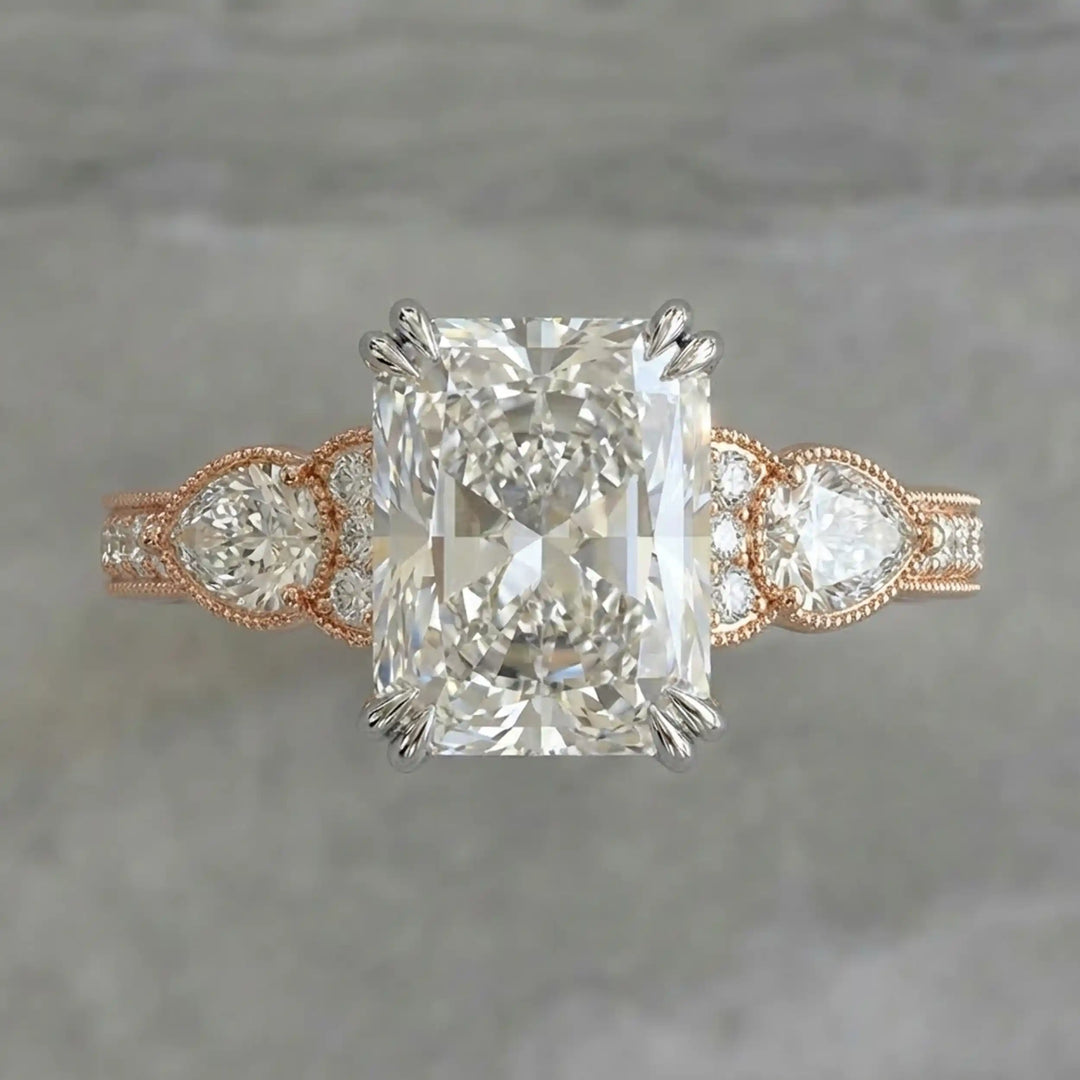 Radiant lab-grown diamond engagement ring with pear side stones displayed on ring stand.
