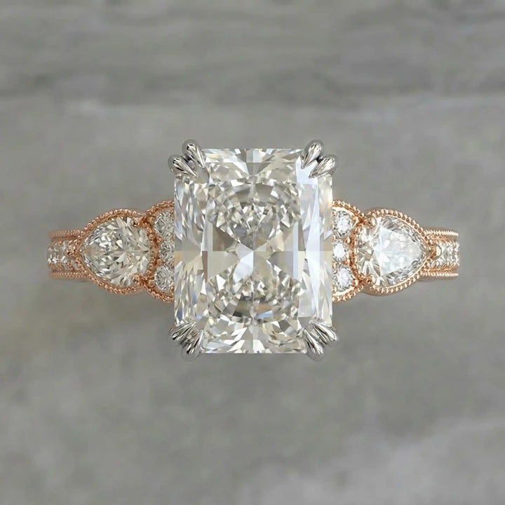 Radiant lab-grown diamond engagement ring with pear side stones displayed on ring stand.
