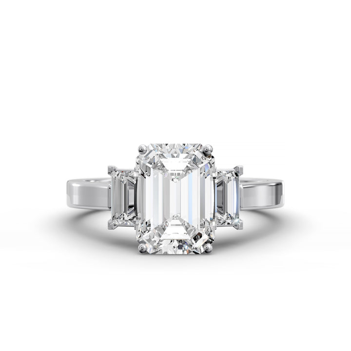 Emerald-cut three-stone diamond engagement ring with matching emerald side stones shown in studio lighting.