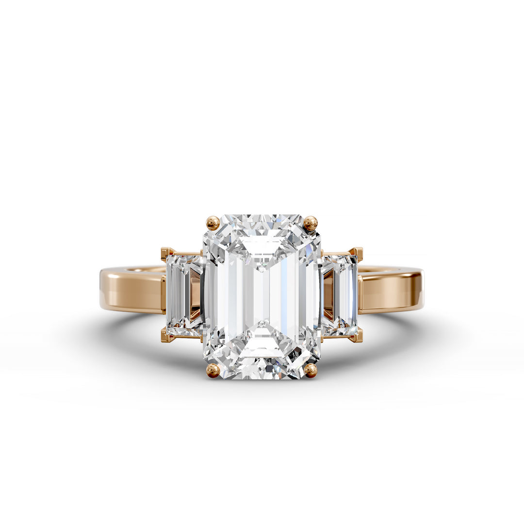 Emerald-cut three-stone diamond engagement ring with matching emerald side stones shown in studio lighting.
