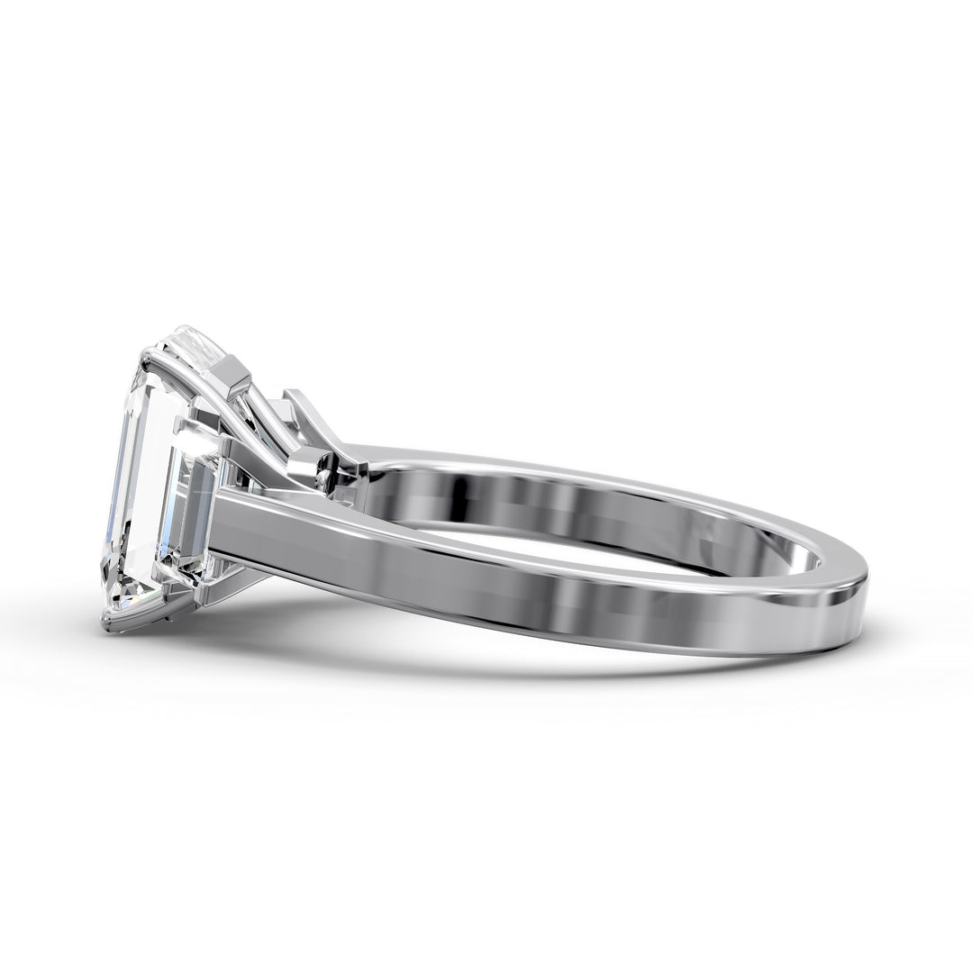 Emerald-cut three-stone diamond engagement ring with matching emerald side stones shown in studio lighting.