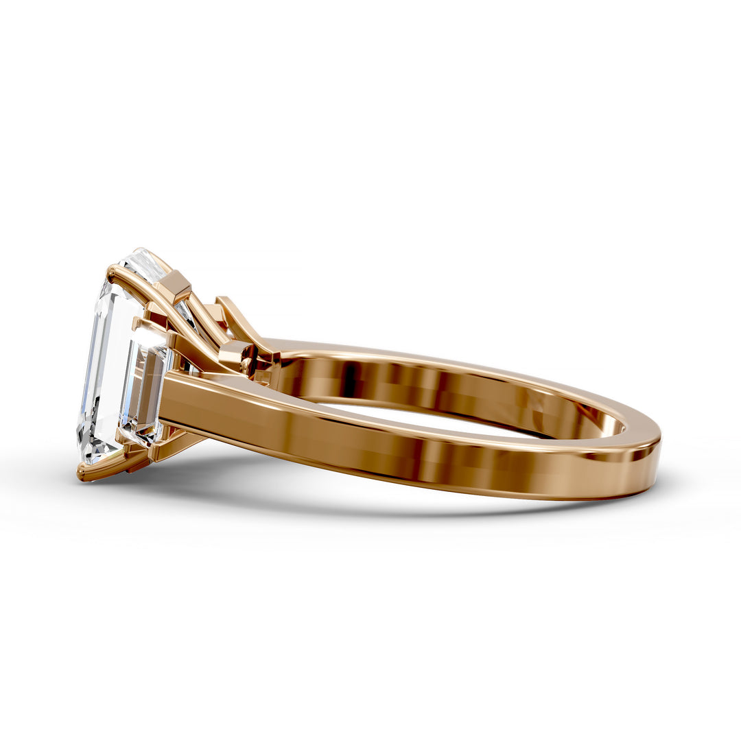 Emerald-cut three-stone diamond engagement ring with matching emerald side stones shown in studio lighting.