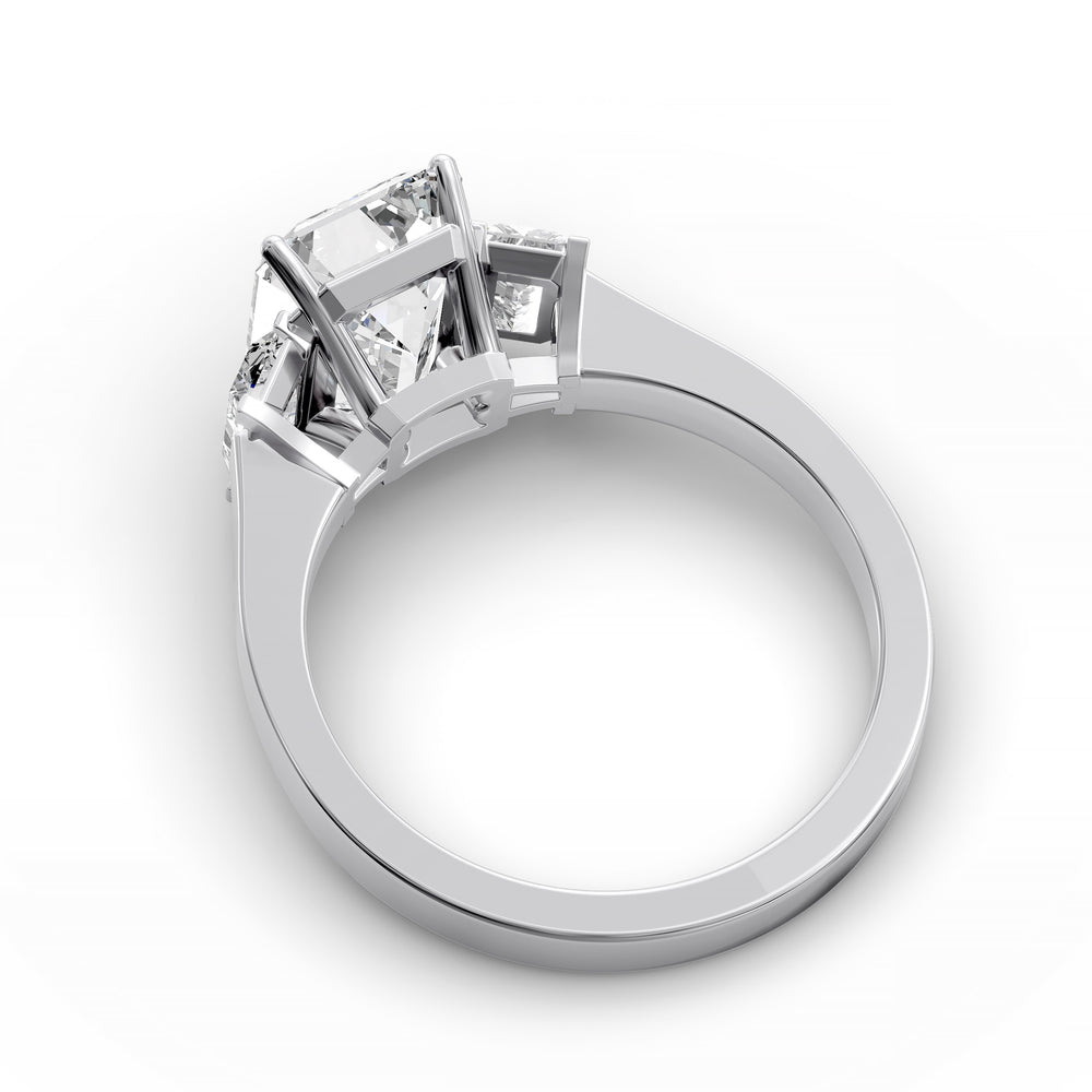 Emerald-cut three-stone diamond engagement ring with matching emerald side stones shown in studio lighting.