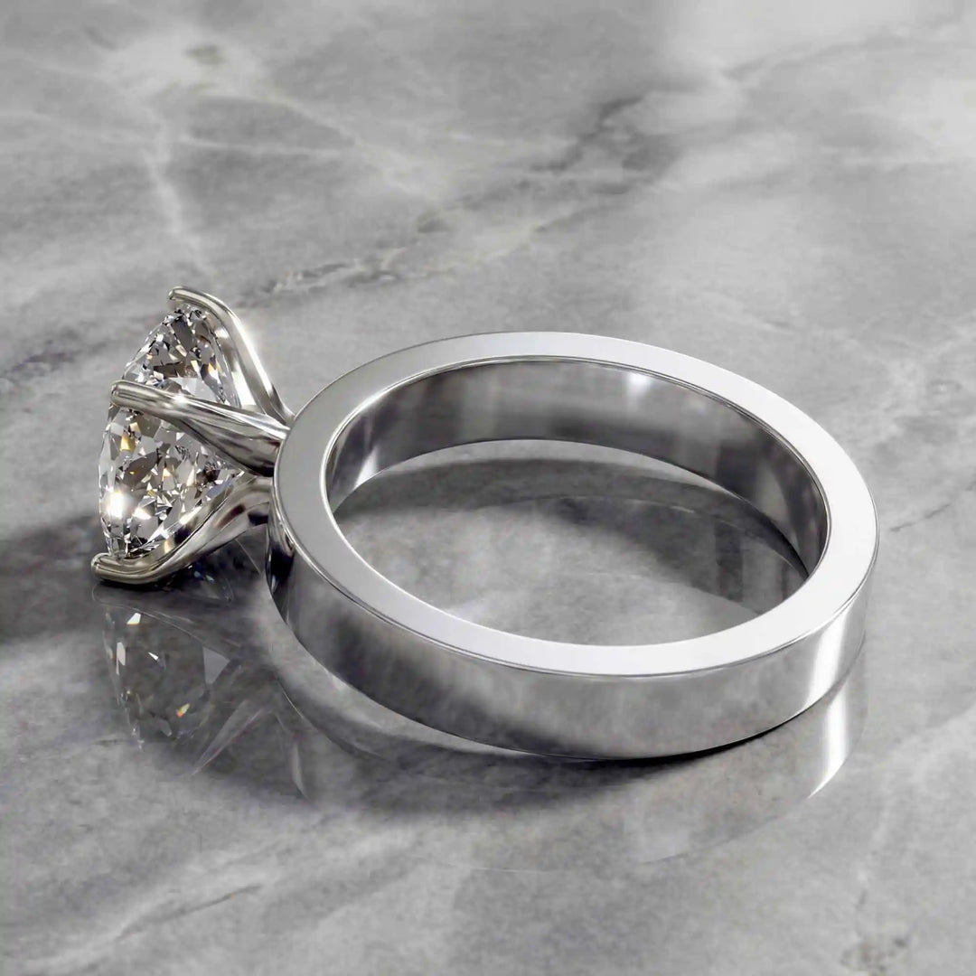 Elongated cushion lab grown diamond solitaire ring on wide flat band shown on display.