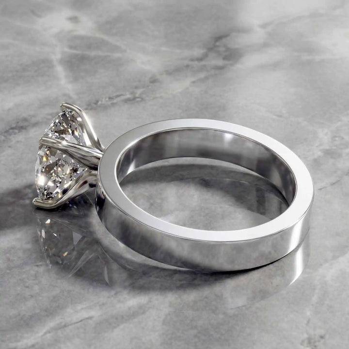 Elongated cushion lab grown diamond solitaire ring on wide flat band shown on display.