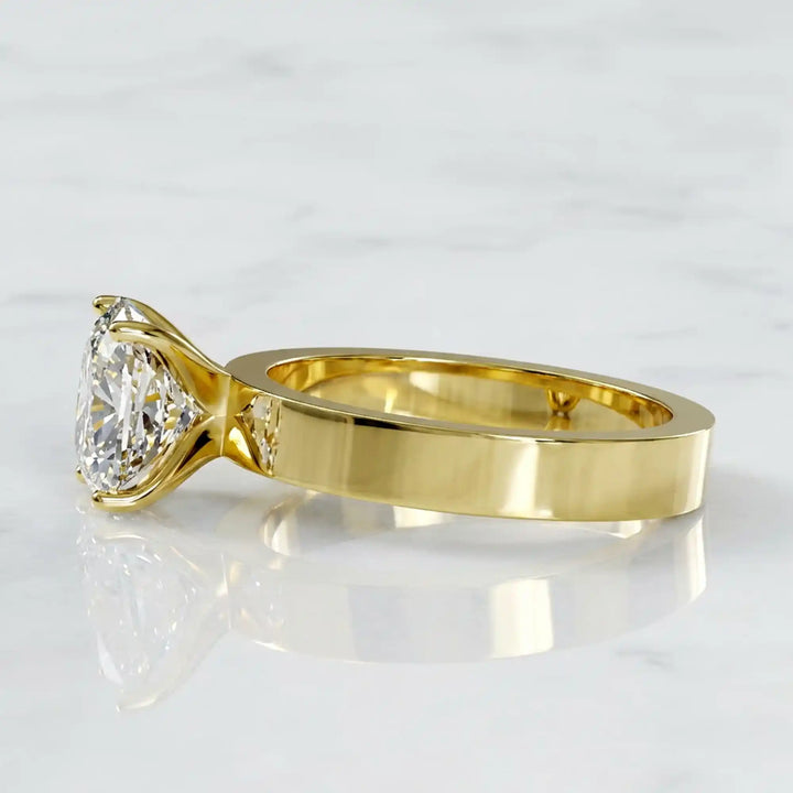 Elongated cushion lab grown diamond solitaire ring on wide flat band shown on display.