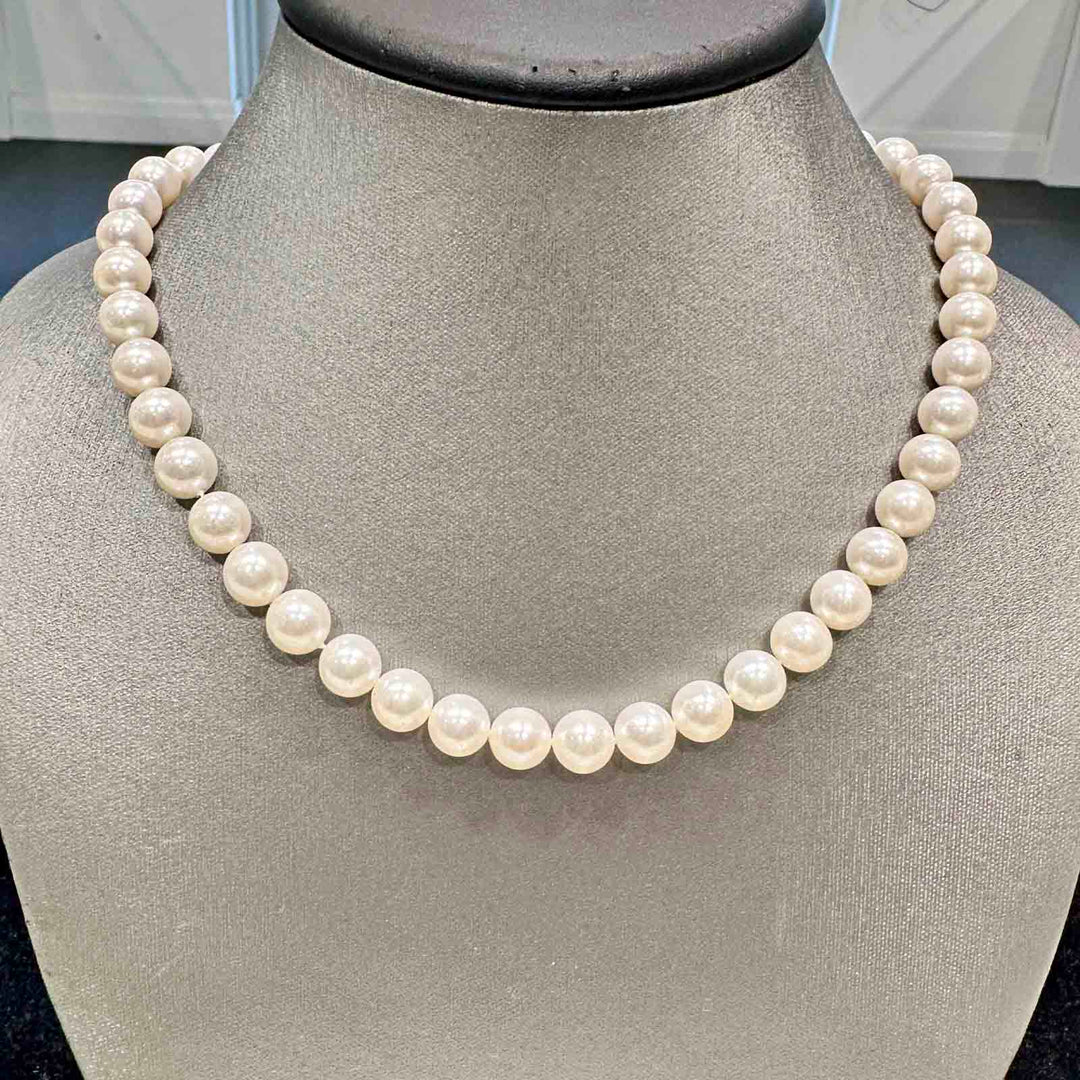 Freshwater pearl necklace with 9.4-8.6mm white pearls of medium luster, minor blemishes, mixed shapes, and a metal clasp.