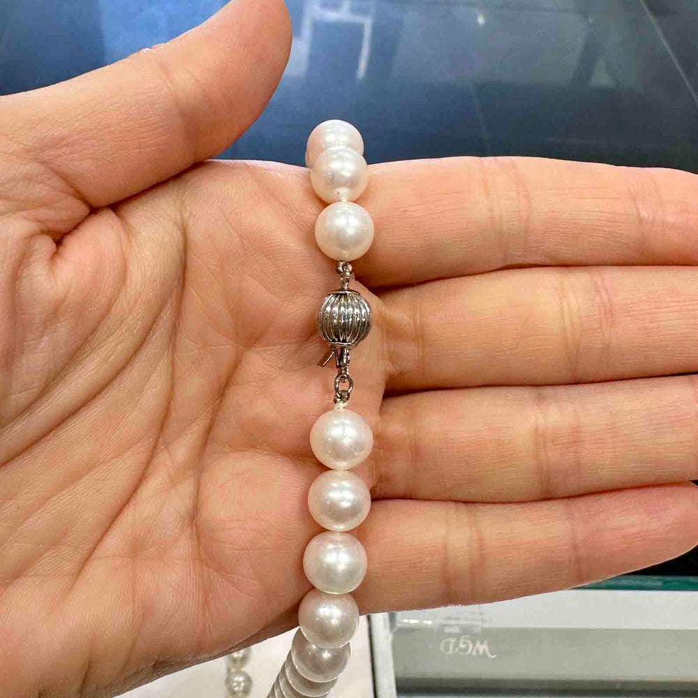 Freshwater pearl necklace with 9.4-8.6mm white pearls of medium luster, minor blemishes, mixed shapes, and a metal clasp.