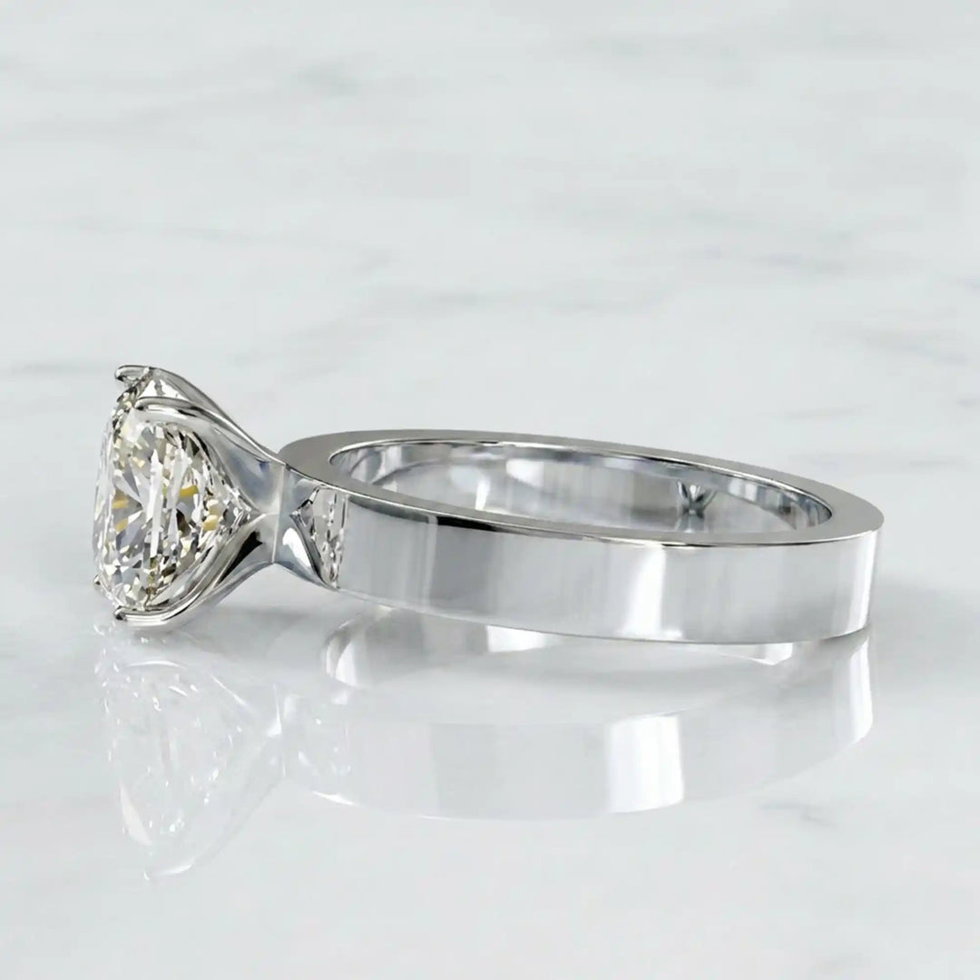 Elongated cushion lab grown diamond solitaire ring on wide flat band shown on display.