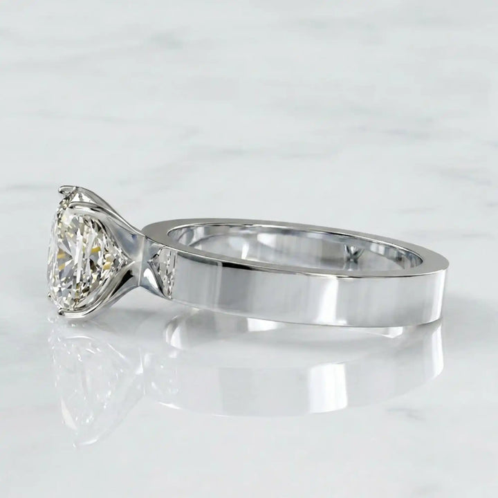 Elongated cushion lab grown diamond solitaire ring on wide flat band shown on display.