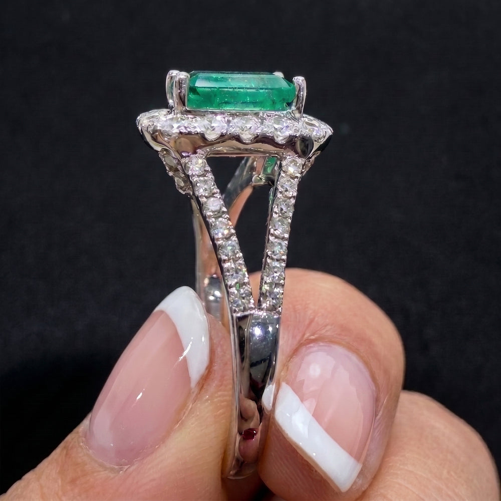 Colombian emerald ring with diamond halo and split shank in 14k white gold.