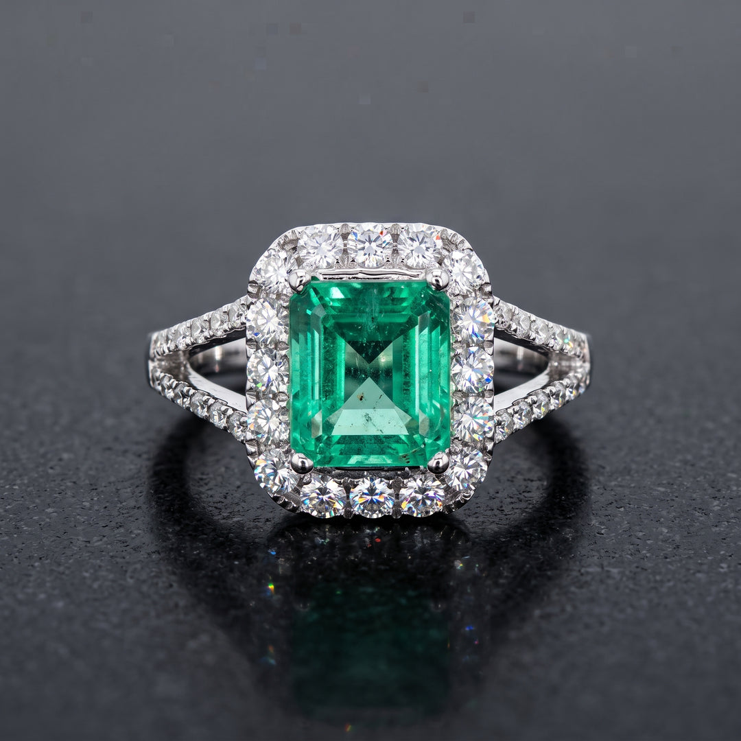 Colombian emerald ring with diamond halo and split shank in 14k white gold.