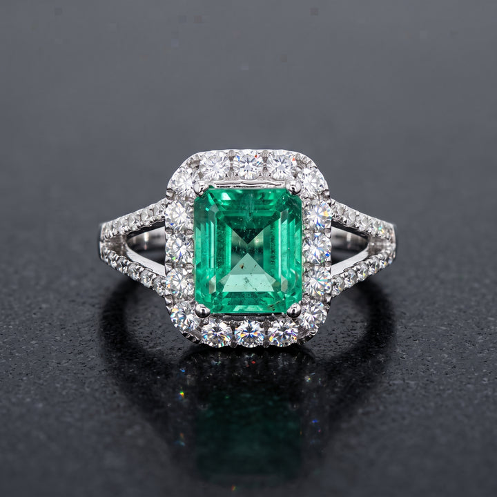 Colombian emerald ring with diamond halo and split shank in 14k white gold.