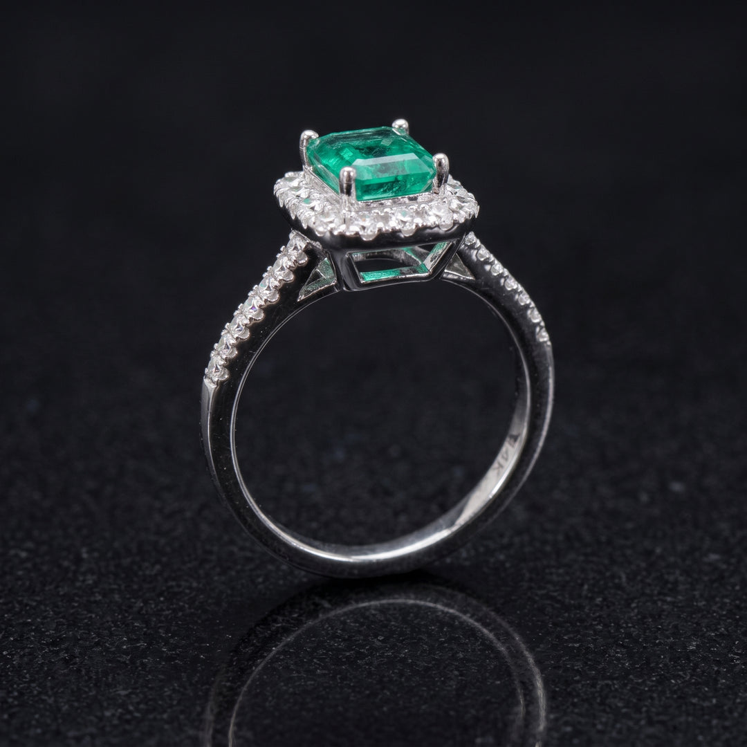 Colombian emerald ring with diamond halo and split shank in 14k white gold.