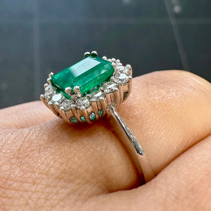 Classic ring with 1.25ct deep green Colombian emerald and diamond halo in 14k white gold.