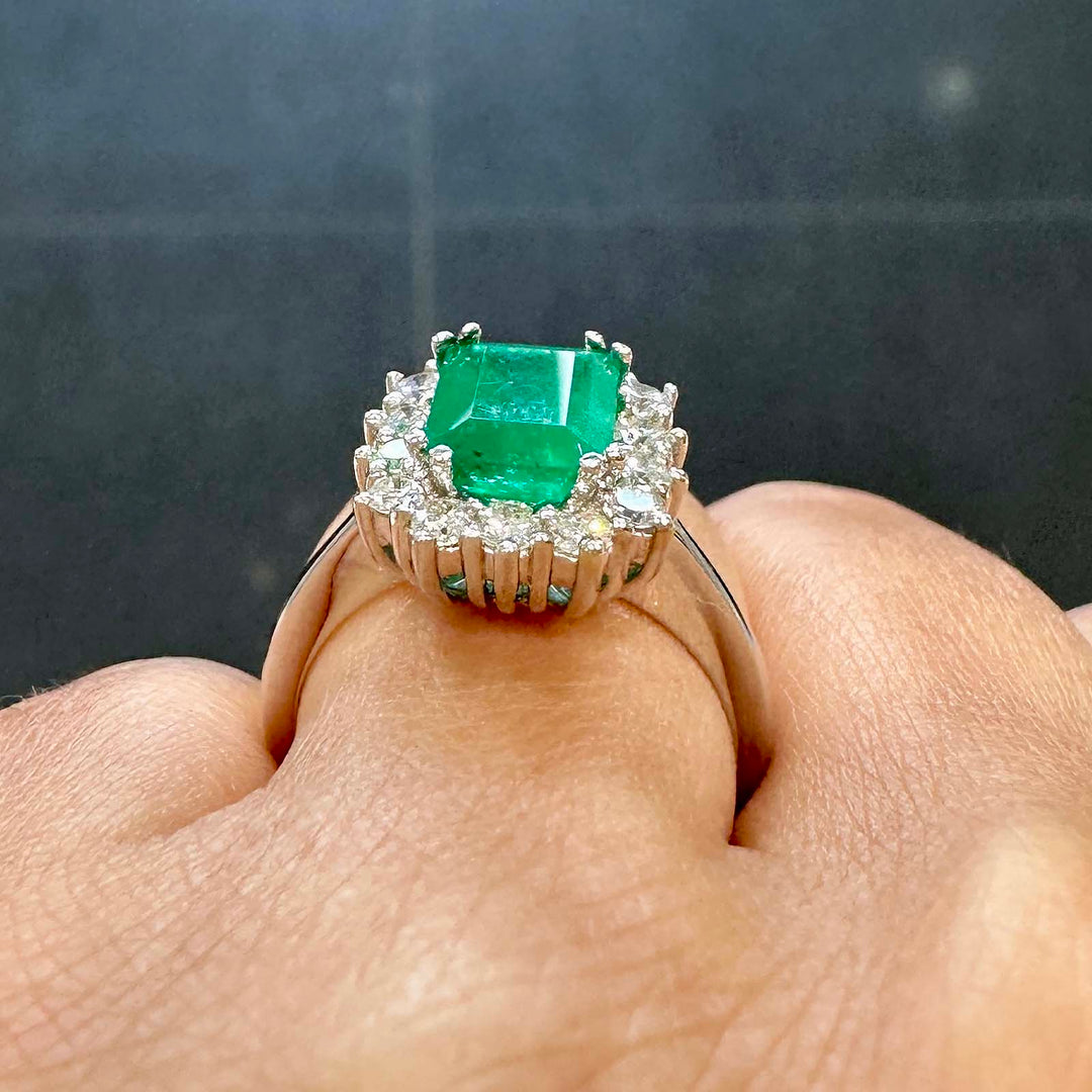 Classic ring with 1.25ct deep green Colombian emerald and diamond halo in 14k white gold.