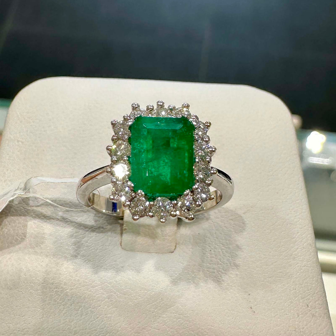 Classic ring with 1.25ct deep green Colombian emerald and diamond halo in 14k white gold.