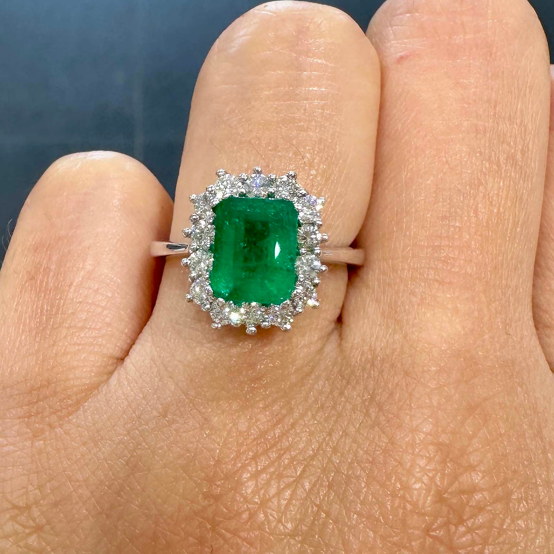 Classic ring with 1.25ct deep green Colombian emerald and diamond halo in 14k white gold.