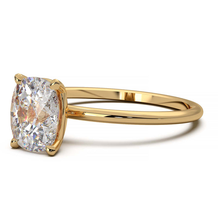 Gold engagement ring featuring a cushion-cut diamond in a four-prong setting.