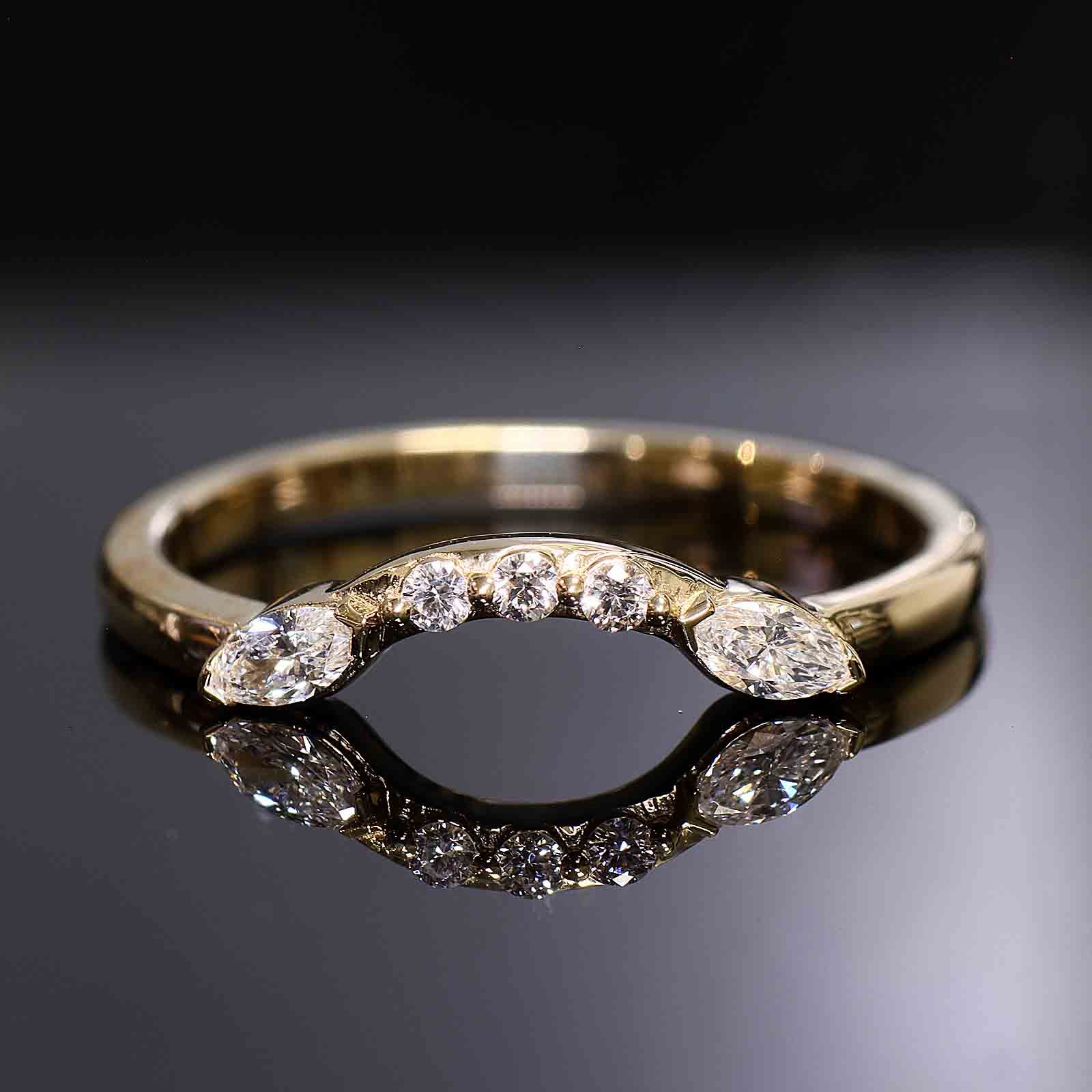 Close-up of a curved wedding band with round and marquise lab-grown diamonds in a shared-prong setting.