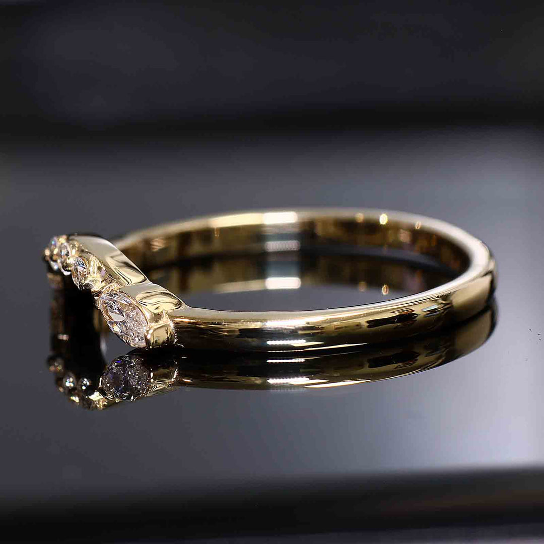 Close-up of a curved wedding band with round and marquise lab-grown diamonds in a shared-prong setting.