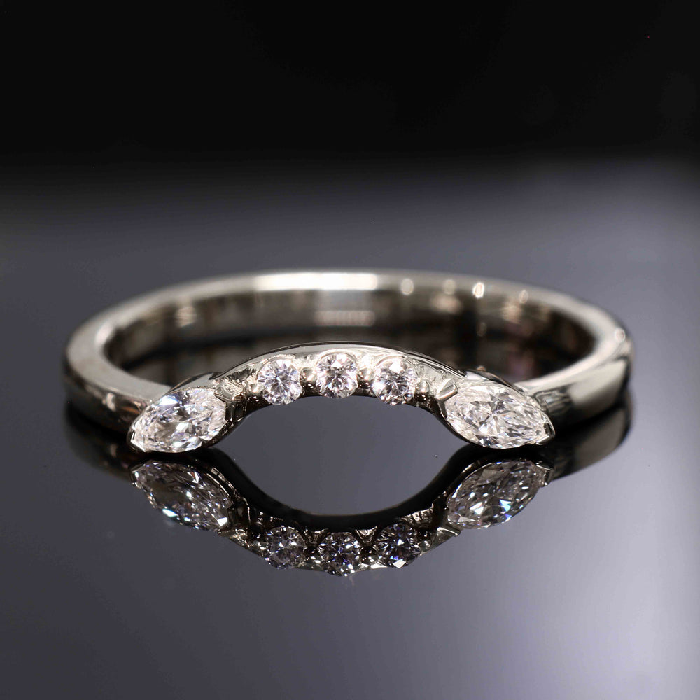 Close-up of a curved wedding band with round and marquise lab-grown diamonds in a shared-prong setting.