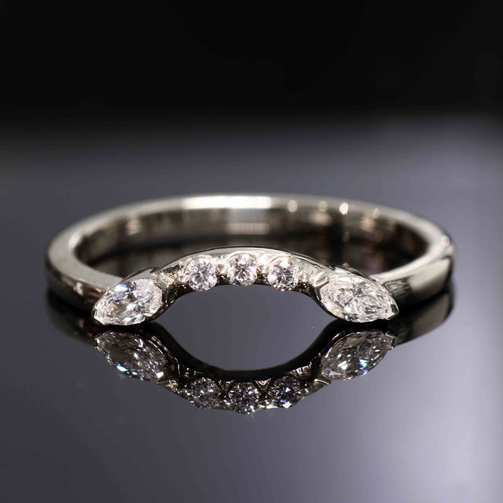 Close-up of a curved wedding band with round and marquise lab-grown diamonds in a shared-prong setting.