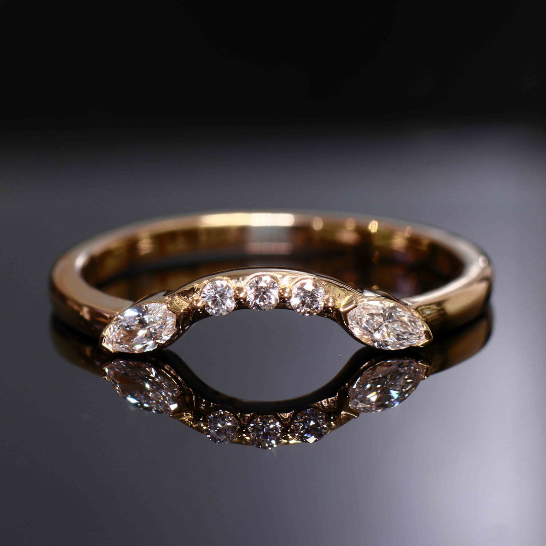 Close-up of a curved wedding band with round and marquise lab-grown diamonds in a shared-prong setting.