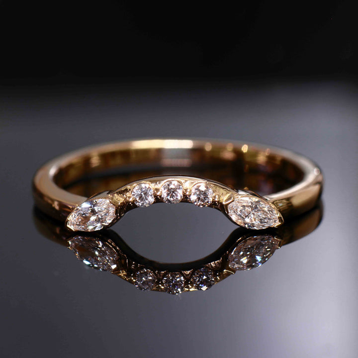 Close-up of a curved wedding band with round and marquise lab-grown diamonds in a shared-prong setting.