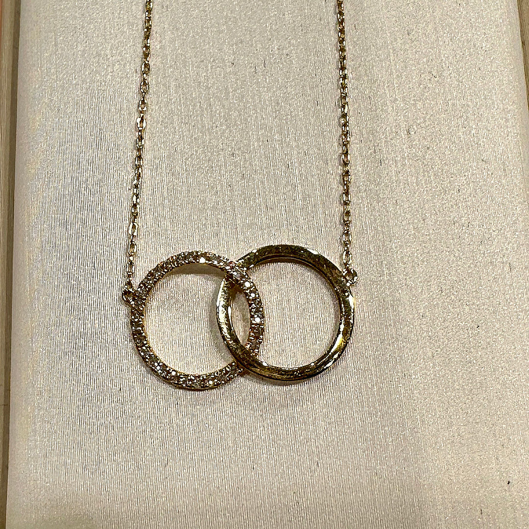 Close-up of a 14K yellow gold infinity necklace with interlocking circles and 0.08ct natural diamonds.