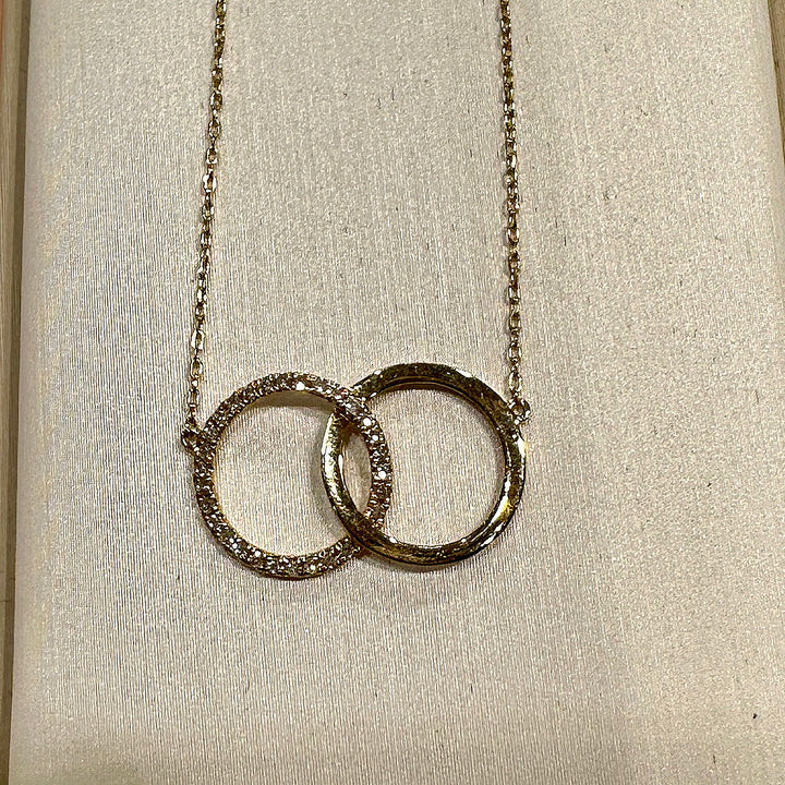 Close-up of a 14K yellow gold infinity necklace with interlocking circles and 0.08ct natural diamonds.