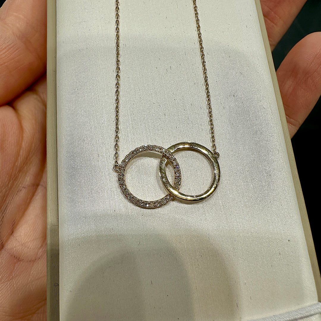 Close-up of a 14K yellow gold infinity necklace with interlocking circles and 0.08ct natural diamonds.