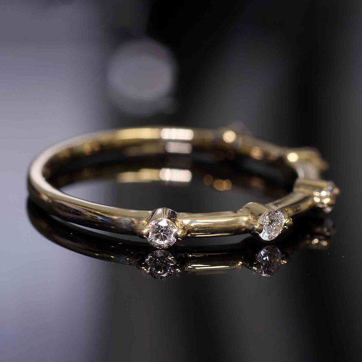 Lab-grown diamond station band with round prongs reflecting on a dark surface.