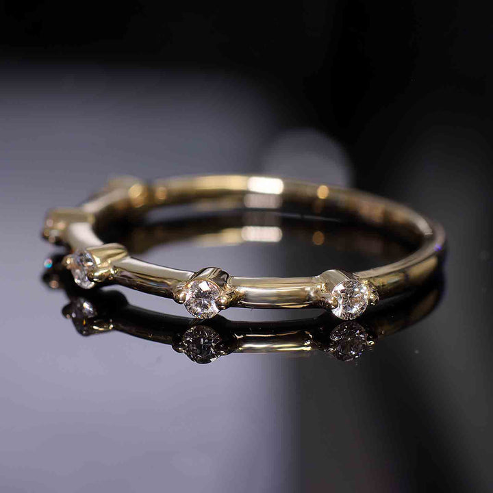 Lab-grown diamond station band with round prongs reflecting on a dark surface.