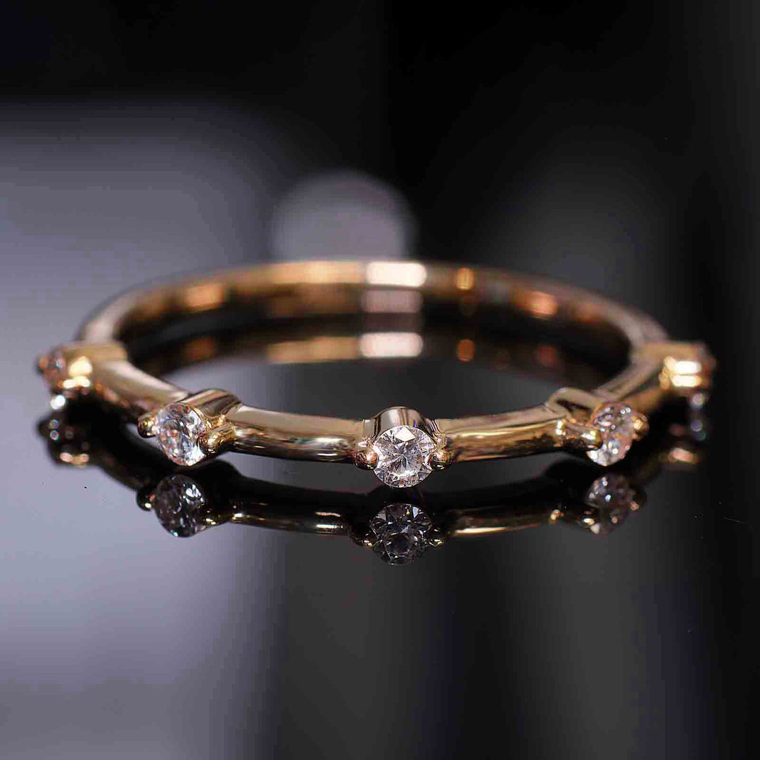 Lab-grown diamond station band with round prongs reflecting on a dark surface.