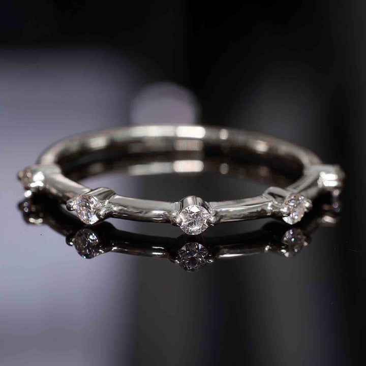 Lab-grown diamond station band with round prongs reflecting on a dark surface.