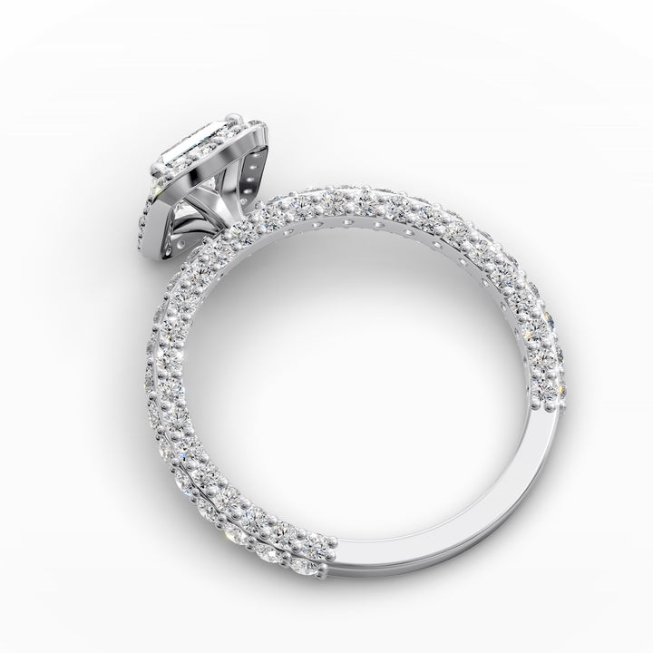 Emerald-cut diamond halo engagement ring with triple prong-set diamond band shown in display view.