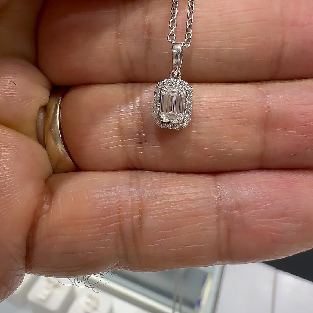 Close-up of a 10K white gold pendant featuring a 0.50ct emerald-cut lab diamond with a halo of smaller diamonds.