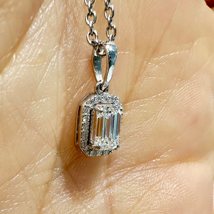 Close-up of a 10K white gold pendant featuring a 0.50ct emerald-cut lab diamond with a halo of smaller diamonds.